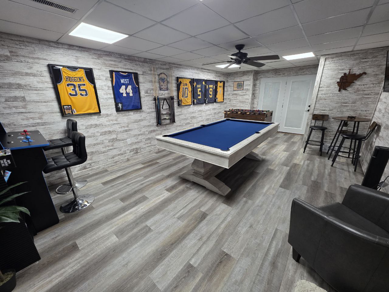WVU themed game room with pool table and framed Mountaineer jerseys